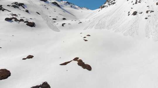 空中：飞过徒步旅行者走向白雪皑皑的山顶，滑雪旅游登山雪