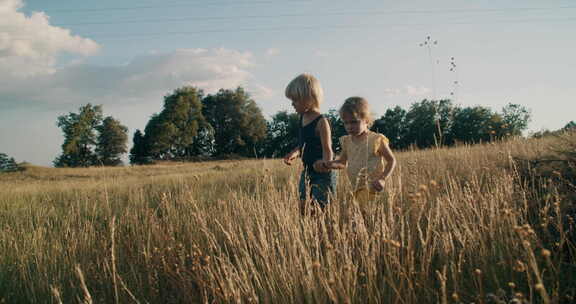 日落时分，兄妹牵着手走在山上的草地上，奶牛在吃草