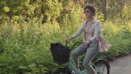 在森林小径上骑自行车的女人