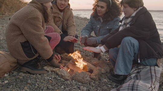 篝火旁聊天和暖手的年轻人