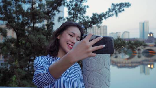 都市女青年成都廊桥河畔游览用手机自拍