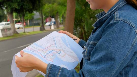 街上的一位妇女拿着一张地图确定自己的位置