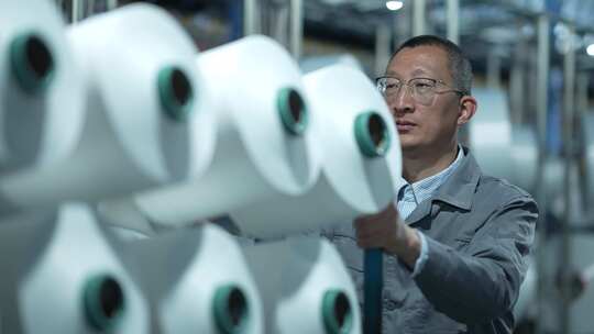 男性工人在化纤纺织厂车间工作