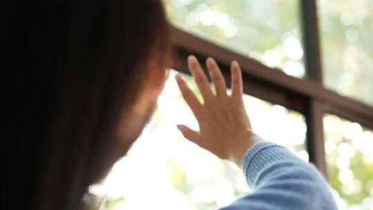 女子窗边伸手触摸阳光画面