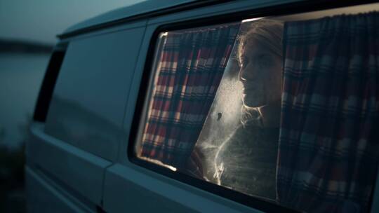 夜晚女人拉上房车的窗帘视频素材模板下载