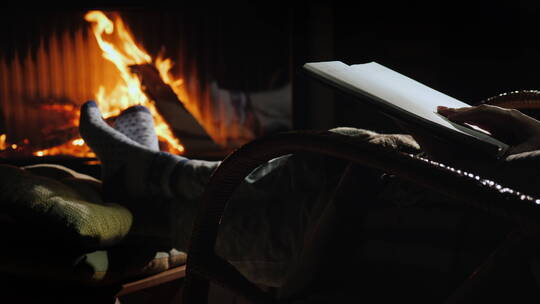 坐在壁炉旁的摇椅上看书的女人视频素材模板下载