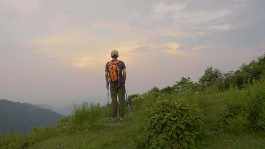 男子持杖登山远眺风景