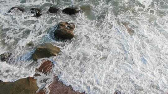 航拍汹涌的海浪冲向岸边的礁石