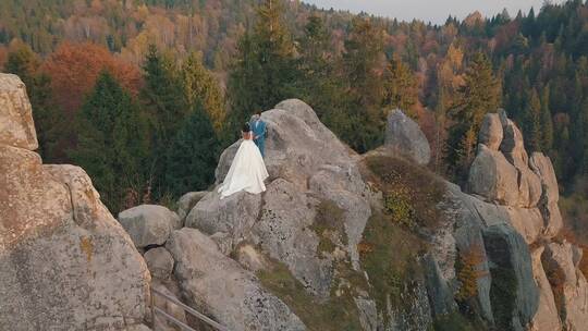 新婚夫妇站在悬崖上拍摄婚纱照