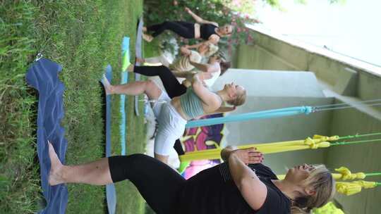 女性在公共公园户外一起锻炼瑜伽和吊床伸展