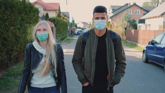 戴着医用口罩的男女走在住宅区的街道上