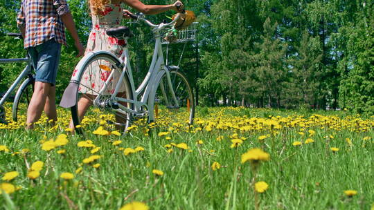 情侣推自行车在草地上走
