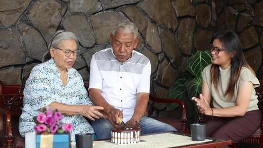 老年亚洲母亲和女儿在家庆祝父亲的生日