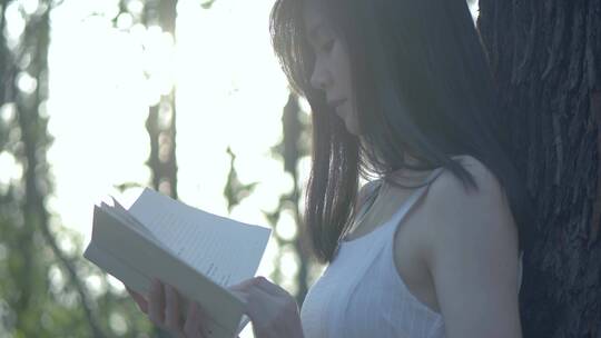 女孩在树林捧着书本阅读视频素材