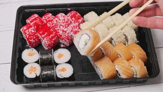 筷子从寿司盒中取出一个寿司卷特写视频素材模板下载