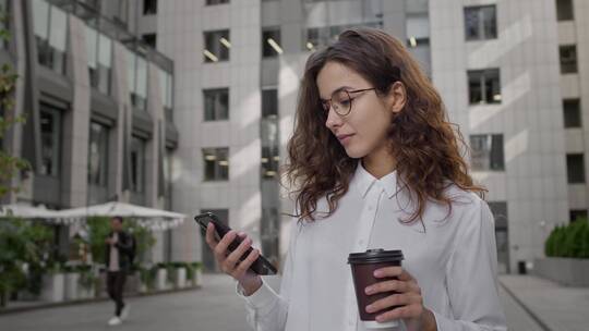 女人拿着咖啡看手机视频素材模板下载