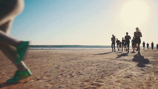 一群在海边沙滩上奔跑慢跑的人