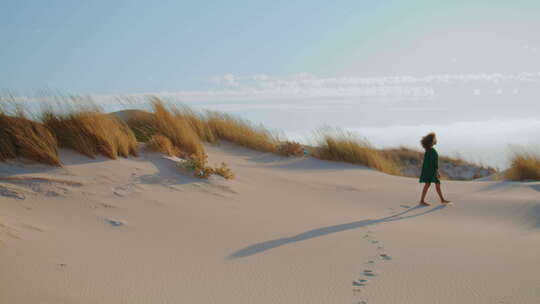无名女孩行走沙漠在沙滩上留下脚印