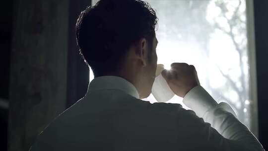 男士窗边手持杯子喝水