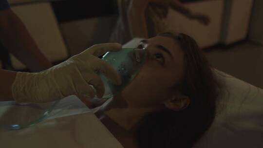 戴氧气面罩的病人躺在病床上