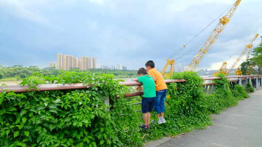 两个小孩在江边爬栏杆看风景