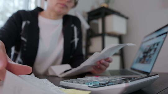 妇女在家中客厅检查账单税银行账户余额和计算费用