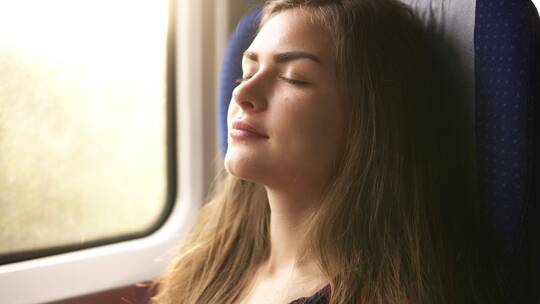 女乘客坐在火车里闭目休息