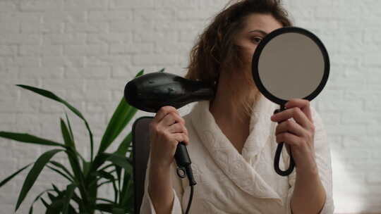 女人洗澡后用吹风机吹干头发