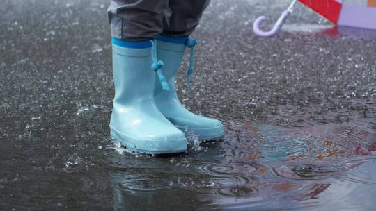 穿着防水靴的人踩地上的雨水