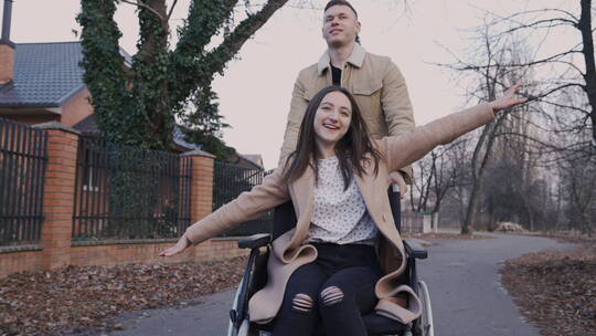 男人和她的残疾朋友坐在轮椅上玩耍