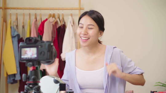 美妆博主呈现美妆坐在前置摄像头录制视频的亚洲女性。