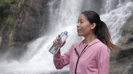 亚洲中国人女性在瀑布下喝水饮用水