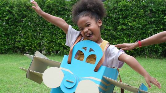 快乐的女孩在草地上玩玩具飞机