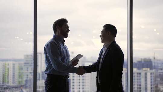 两个商人在现代背景下握手和交流的会议剪影