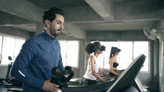 4K运动男女戴着虚拟现实眼镜在健身房的跑步机上慢跑锻炼