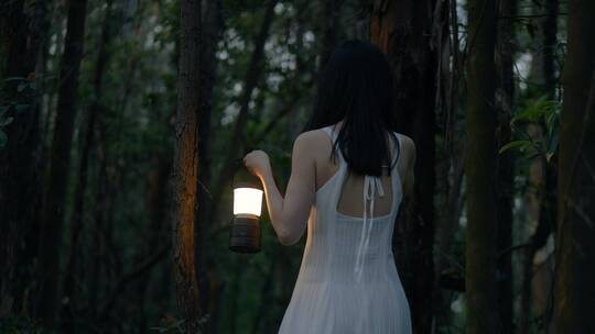 女孩提着灯在黑暗的树林行走