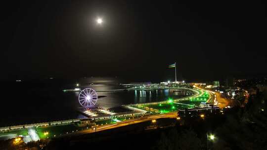 海洋和月球路径交通背景下的夜间摩天轮大城