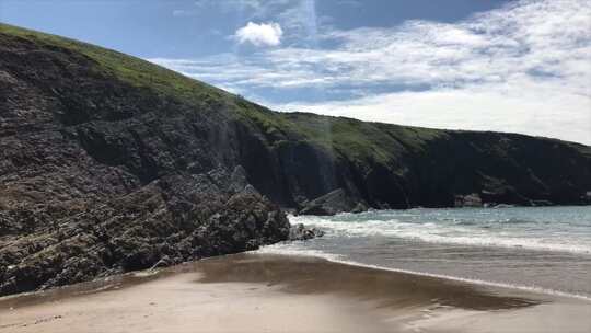 威尔士的沙滩在卡迪根湾崎岖的岩石海岸线前