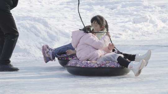 小女孩坐雪圈在冰上滑行