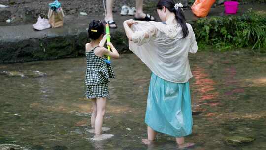 溪河里妈妈带着女儿玩水枪