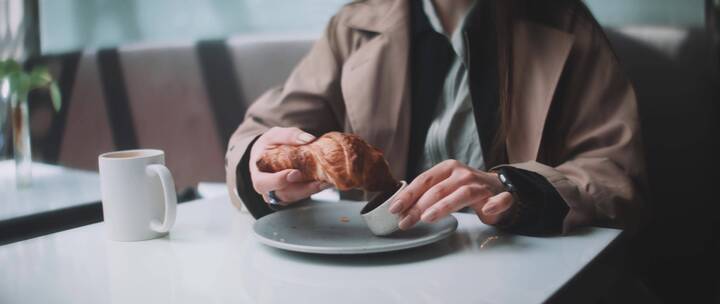 女人在咖啡馆吃羊角面包