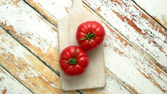 两个新鲜的生态西红柿放在白色木质砧板上