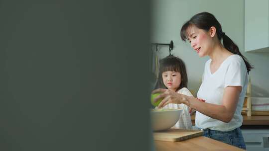 爱美丽的父母妈妈和小兄弟姐妹可爱的女孩孩子感到快乐享受在厨房吃苹果