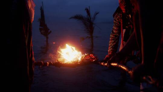 夜幕下在河边进行篝火的人