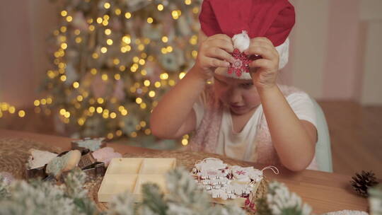 小女孩用圣诞装饰品装饰她的圣诞帽