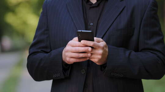 特写男性双手身穿黑色正装的未知男子在社交媒体使用中手持智能手机聊天视频素材模板下载