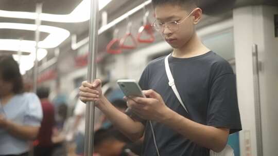 男生在地铁站看手机