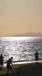 海南三亚黄昏阳光下沙滩度假的人群剪影