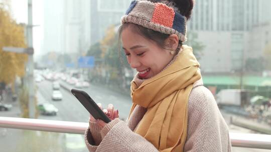 都市女青年秋天城市街头玩手机戴着围巾