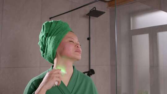 漂亮的中年亚洲女性使用微电流面部按摩器进